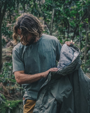 Man in the forest with a t-shirt and a rain jacket 