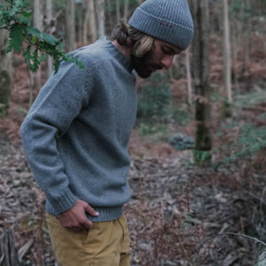 Man in the woods wearing an Indagatio's grey sweater made of wool.